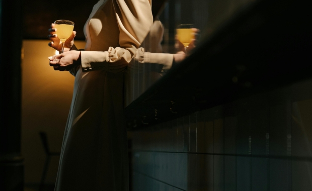 A woman leaning on a bar with a cocktail in hand 